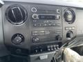 The dashboard of a 2014 Ford F-250 SD featuring a radio control panel with buttons and knobs for audio settings and climate control