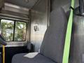 A gray passenger seat inside a 2017 Freightliner MT45 with a green seatbelt