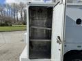 The image shows the open rear compartment of a 2024 Ford F-550 featuring metal shelving and hooks inside the storage area