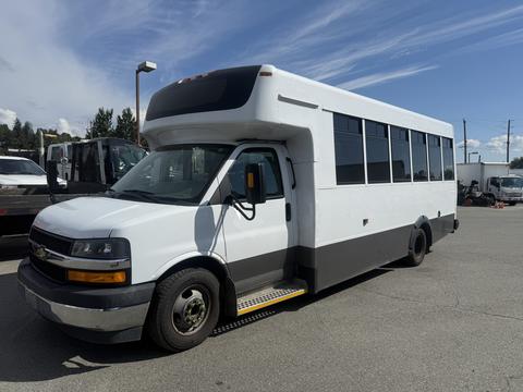 A 2020 Chevrolet Express bus with a white exterior and a black lower section featuring large windows along the sides and a high roof design