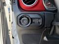 Close-up of the control panel in a 2021 Jeep Wrangler featuring knobs for headlights and fog lights with a red and black design
