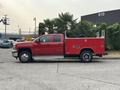 A red 2015 Chevrolet Silverado 3500HD with a flatbed and palm trees loaded in the truck bed