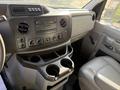 Interior dashboard of a 2012 Ford Econoline E-450 featuring audio controls and cup holders