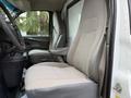 Interior view of a 2015 GMC Savana showing two front seats in light gray upholstery with a textured pattern and a console between them
