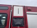 A red 2006 E-One Typhoon fire truck with a silver diamond plate storage compartment and a black canvas cover on the side
