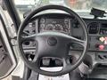 Interior view of a 2013 Freightliner 114SD featuring a large steering wheel with controls and a dashboard displaying various gauges and indicators