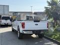 A white 2021 Ford F-150 truck with chrome accents and silver storage boxes in the truck bed