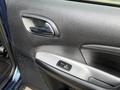 Close-up of the interior door panel of a 2013 Dodge Journey featuring a silver door handle a power window switch and textured dark material