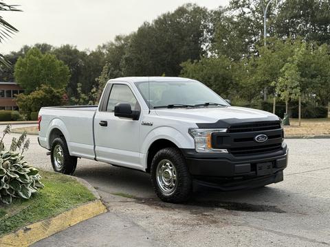A 2018 Ford F-150 in silver with a black front grille and chrome accents parked with a single cab and standard bed