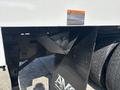 Close-up of a black metal bracket attached to the chassis of a 2019 Freightliner M2 106 with warning label and visible rear tires in the background