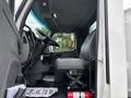 Side view of the interior of a 2025 Peterbilt 536 showing the driver's seat and steering column with floor mats and a fire extinguisher visible on the floor