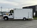 A 2012 Ford F-550 truck with a white cargo box, featuring a side entrance and large rear compartment, parked on a lot