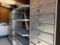 A 2009 Kenworth T270 with multiple silver storage drawers and shelves in the foreground, showcasing a functional design for tool or equipment storage.
