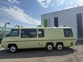 A 1976 GMC Motorhome in yellow with a streamlined shape featuring large windows and three axles