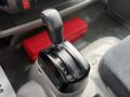 Gear shift lever of a 2018 Hino 195 truck positioned between the driver and passenger seats with a red toolbox visible behind it