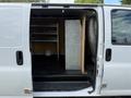 A 2018 GMC Savana van with an open side door revealing a storage area featuring metal shelving and a wooden panel beside a storage unit