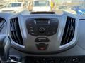 The image shows the dashboard of a 2015 Ford Transit featuring a central control panel with buttons for audio settings and a digital display indicating radio frequency and temperature