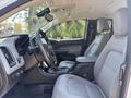 Interior view of a 2017 Chevrolet Colorado featuring a black steering wheel gray seats and a central console with controls and cup holders