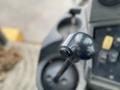 Close-up of the gear shift lever of a 2012 John Deere 310SJ tractor showing a circular knob and a black rod extending vertically
