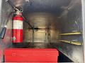 Interior view of a storage compartment from a 2007 Ford F-450 featuring a red fire extinguisher and a red toolbox against a metal surface