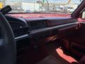 Interior view of a 1995 Ford F-250 featuring a red dashboard with controls and a digital clock on the display panel