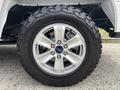 A close-up of a silver alloy wheel with a large black tire featuring rugged tread patterns mounted on a 2017 Ford F-150
