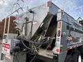 A 2013 Freightliner 114SD equipped with a silver truck bed and visible hydraulic components along with safety signage on the side