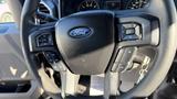 Steering wheel of a 2016 Ford F-150 featuring buttons for audio control and cruise settings with the Ford logo in the center
