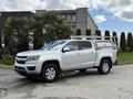 A 2018 Chevrolet Colorado pickup truck in silver with a utility rack on the bed parked on a concrete surface