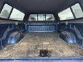 The interior of a 2006 Dodge Ram 2500 truck bed with a carpeted lining and a rubber mat showing dirt and wear