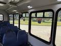 Interior view of a 2020 Chevrolet Express bus showing empty blue seats and large windows with metal frames
