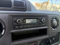 The image shows the dashboard of a 2023 Ford E-450 featuring a car radio display with buttons for volume tuning and radio station selection