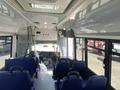 Interior view of a 2020 Chevrolet Express bus showing a row of blue seats and the driver's area at the front