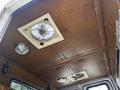 The interior ceiling of a 1995 Freightliner FL086 showing two ceiling fans and a dome light with a texture resembling brown leather or vinyl