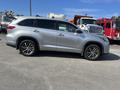 A silver 2018 Toyota Highlander is parked with its side view visible showcasing its sleek design and alloy wheels