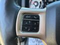 Close-up of a steering wheel control panel featuring various buttons including navigation and phone controls in a 2015 RAM 1500