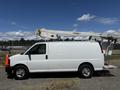 A white 2017 Chevrolet Express van with an extended ladder rack on top and a cherry picker attachment for elevated work
