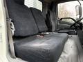 The interior of a 2015 Hino 195 showing a driver’s seat and a passenger bench seat both covered in dark fabric with seatbelts visible