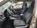 Interior view of a 2016 Subaru Forester showing two front seats with black fabric upholstery and a steering wheel with various controls