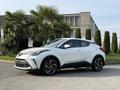 A white 2021 Toyota C-HR parked with a modern design featuring angular lines, a prominent front grille, and stylish alloy wheels