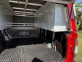 Interior of a 2018 GMC Canyon truck bed featuring a black rubber liner and a metal storage compartment on the left side