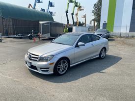 A silver 2013 Mercedes-Benz C-Class coupe with sporty design and alloy wheels parked on a concrete surface