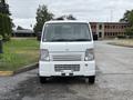 A 2010 Suzuki Carry van with a white exterior and a simple front design featuring clear headlights and a prominent grille