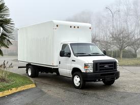 A 2019 Ford Econoline box truck in white with a large enclosed cargo area and black grille parked on a pavement