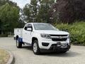 A white 2017 Chevrolet Colorado pickup truck with blue accents parked on a paved road featuring a front-mounted winch and toolbox in the truck bed