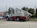 A 2012 International 7300 Workstar truck with a red and white body and an elevated work platform mounted on the back