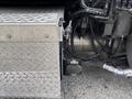 A metallic step box with a diamond plate texture attached to the side of a 2013 Kenworth T370 truck featuring various pipes and connections visible nearby