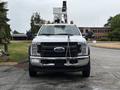 A 2018 Ford F-550 with a white exterior is positioned front-facing featuring an elevated work platform and safety lights on top