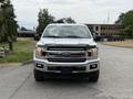 A 2018 Ford F-150 with a shiny silver exterior and a prominent black grille in the foreground