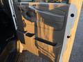 A tan interior door panel of a 2015 GMC Savana showing the door handle and a storage compartment